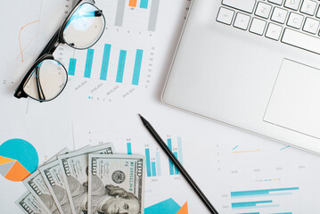 Business infographics and charts, economic reports with graphs, laptop, money on office desktop