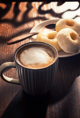 Hot latte and donuts on wooden table behind window