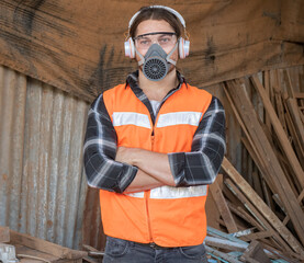 Handsome Caucasian carpenter craftsman wearing safety gear working with hardwood using a miter saw to cut a piece of wood in the workshop. Manufacture of wood products.