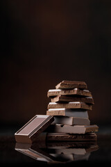 Broken chocolate pieces on dark background. Stack of dark chocolate. Chocolate concept