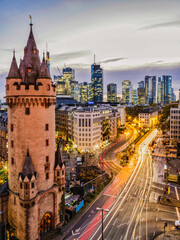Obraz premium Vertical shot of Eschenheim Tower, old and new Frankfurt city buildings illuminated at night