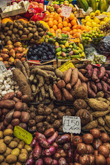 greengrocer selling fruits and vegetable at traditional italian market stall - displayed product name and price