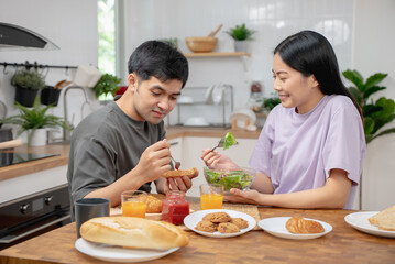 Obraz na płótnie Canvas happy family together. Asian couple eating breakfast in the kitchen.