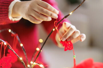 Asian Woman decorated house for Chinese New Year Celebrations. putting traditional pendant to the Chinese Lunar New Year for good luck. Chinese word means blessing