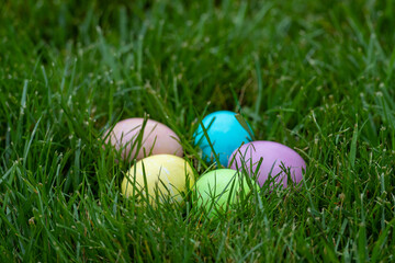Multiple colorfully dyed Easter eggs in green grass with a shallow depth of field and copy space