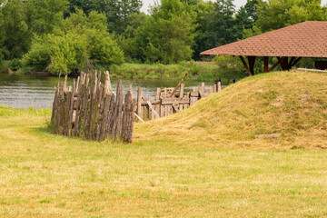 Stockade and shed on a green meadow against the background of a river and forest on a sunny day. Summer.