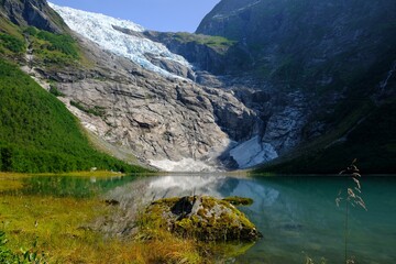 Boyabreen Glacier and a glacial lake  Jostedalsbreen National Park  in Norway. A small tent stands at the foot of the glacier.