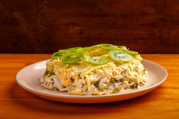 Salad with chicken and kiwi malachite bracelet on a beige plate on a gray table.