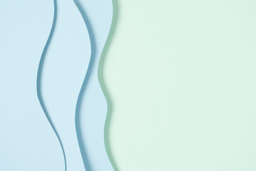 Abstract colored paper texture background. Minimal paper cut composition with layers of geometric shapes and lines in light blue color on green color background. Top view