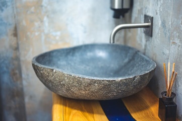 Luxury black stone washbasin with faucet on wooden countertop in minimalist modern bathroom....