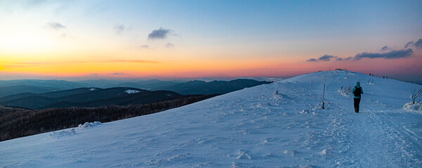 backpacker girl walks along the top of snowy mountains bieszczady at sunset, winter sunset seen from the top of the mountain wielka rawka