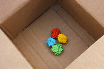 A cardboard box with crumpled colorful paper balls inside