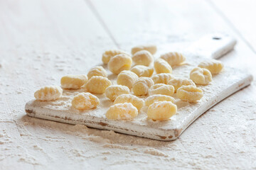 Fototapeta na wymiar Traditional homemade raw italian potato gnocchi on white wooden background