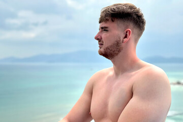 handsome and sporty, topless guy enjoying and sunbathing in the sun on the rooftop of a lux hotel spa suite with sea,ocean view on vacation