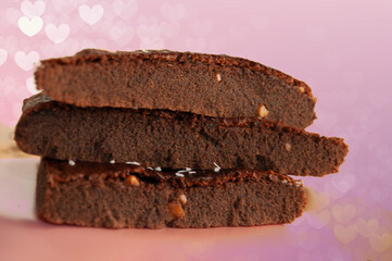 Closed stacked side view homemade chocolate brownies, with pink glitter background. 