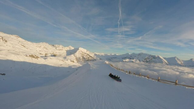A Snake Gliss toboggan train descends a straight line down a ski slope in the Alps