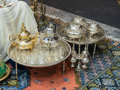 Set of decorated vessels, teapots and cups for the traditional Moroccan tea ceremony on decorated trays in FITUR 2022