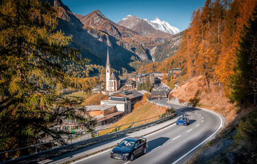 Incredible scenery of European Alps in sunny morning. Heiligenblut church in Austria with Grossglockner peak in background Grossglockner High Alpine road is a most popular place of travel - obrazy, fototapety, plakaty