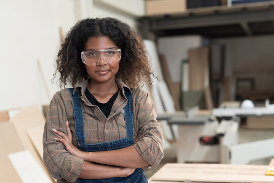 African American female carpenter standing with arms crossed at wood processing plants. Female carpenter working at wood workshop