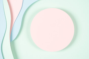 Blank pink round geometric shape podium platform on paper cut abstract geometric shape pastel pink, blue and green background. Top view mock up for product display