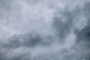 Storm clouds floating in a rainy day with natural light. Cloudscape scenery, overcast weather above blue sky. White and grey clouds scenic nature environment background