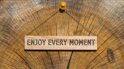 ENJOY EVERY MOMENT is written on the wooden surface. Wooden Concept