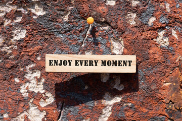 ENJOY EVERY MOMENT is written on the wooden surface. Wooden Concept