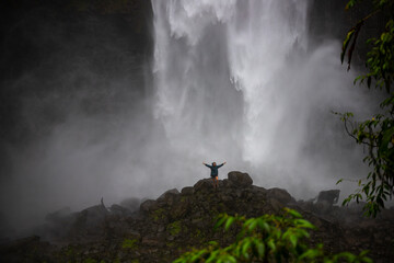 girl standing in front of san fernando waterfall in costa rica; huge waterfall in the middle of...