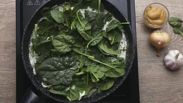 A large pile of spinach lies in a pan