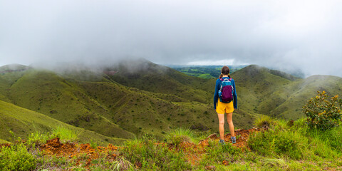 Obraz premium backpacker girl walks along ridge amid cerro pelado mountains during cloudy, misty weather; hiking in green mountains in Costa Rica, Costa Rica rainforests