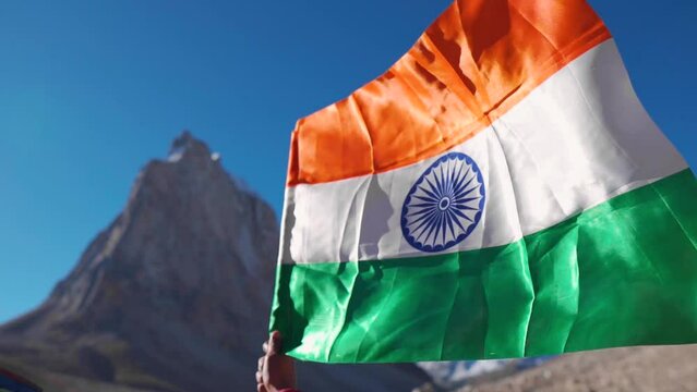 Close up shot of man holding Indian flag in background of Gumbok Rangan mountain at Zanskar, Ladakh, India. Tri color Indian flag fluttering. Republic Day  background