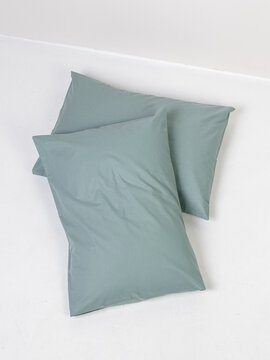 Two pillows in green pillowcases on white background