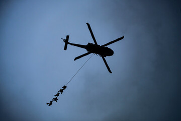 Soldiers hanging from a ​helicopter
