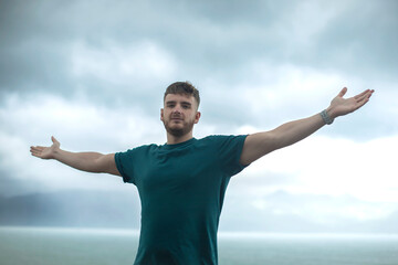 Fototapeta na wymiar happy handsome free guy, young calm relaxed carefree man traveler with open raised hands enjoy sea, ocean view, person feeling good, breath deep deeply fresh air. Freedom, travel, happiness concept