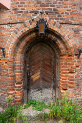Entrance to a historic brick building with a hanging lantern above the door. Wall.