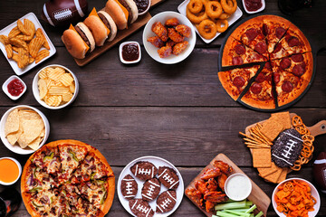 Super Bowl or football theme food frame. Pizza, hamburgers, wings, snacks and sides. Above view on...