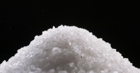 Close up shot of salt granules falling. Spice particles being dropped. Bath cosmetic salt forming a...