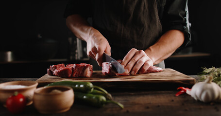 Chef sharpening his knife in front of raw piece of steak. Cooker preparing his tools for cutting...