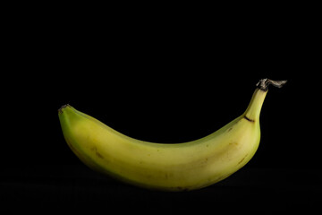 Ripe natural healthy banana isolated on black background. This fruit is ready to eat once peeled from its skin