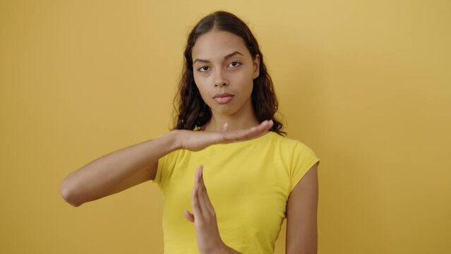 Young african american woman doing timeout gesture with hands over isolated yellow background