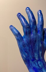 Dłoń pomalowana na niebiesko na jasnym tle. Kolorowa ręka i niebieskie palce