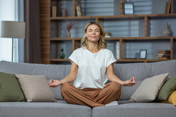 Senior woman at home resting meditating with eyes closed sitting on sofa in living room, housewife...