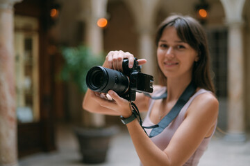 Girl photographer with a camera at work on the set in the studio room. Young beautiful woman - a professional photographer with a camera and a flash takes pictures
