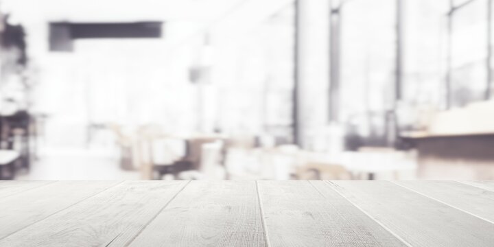 Empty wooden table top with out of focus lights bokeh modern white coffee shop background
