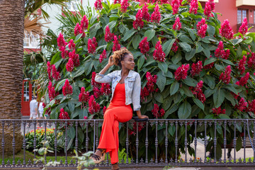 Happy afro woman on background of flowers dressed in red