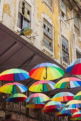 Umbrellas in Pink street in Lisbon, Portugal, with a run-down building in the background