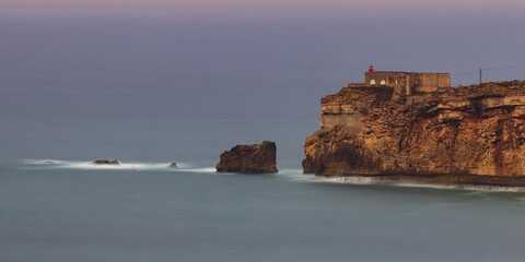 Long exposure panoramic photo of the fort of São Miguel Arcanjo and rocks in Nazaré, Portugal
