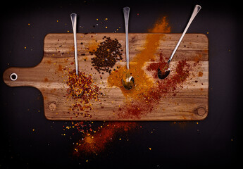 Condiment with spoons on wood and black background.