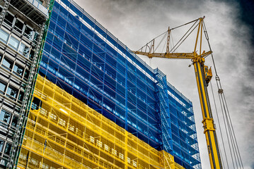 Baustelle mit Gerüst und Bauschutznetz in den Nationalfarben der Ukraine als Symbol für den Wiederaufbau an einem Gebäude in der Frankfurter Innenstadt - obrazy, fototapety, plakaty