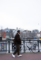 Young man walking on the bridge in Amsterdam in winter. 